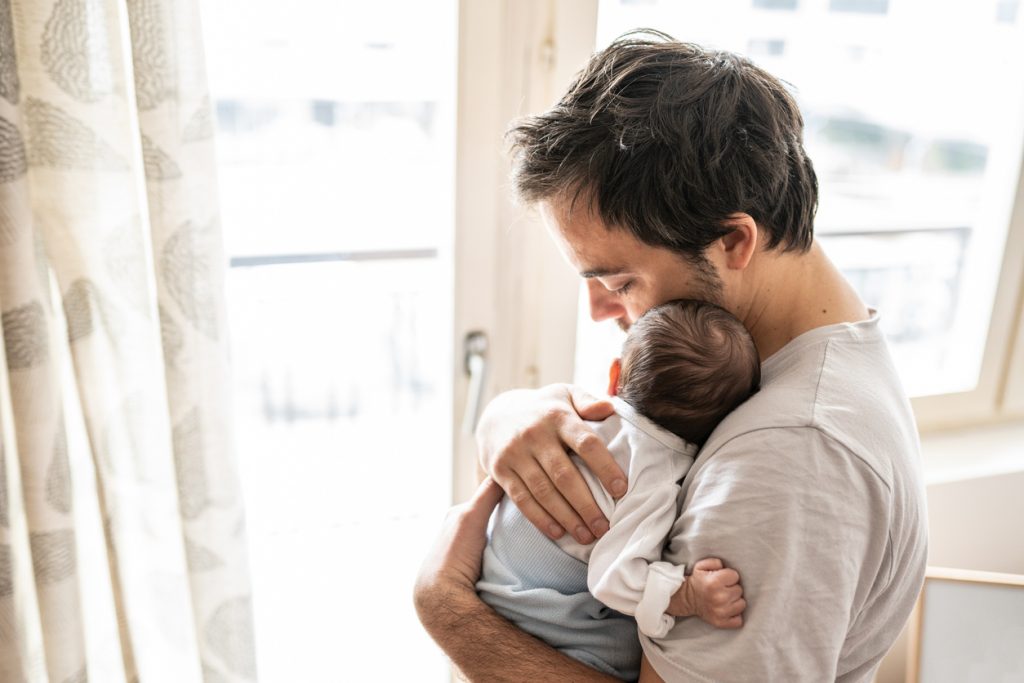 Gay man embracing child.