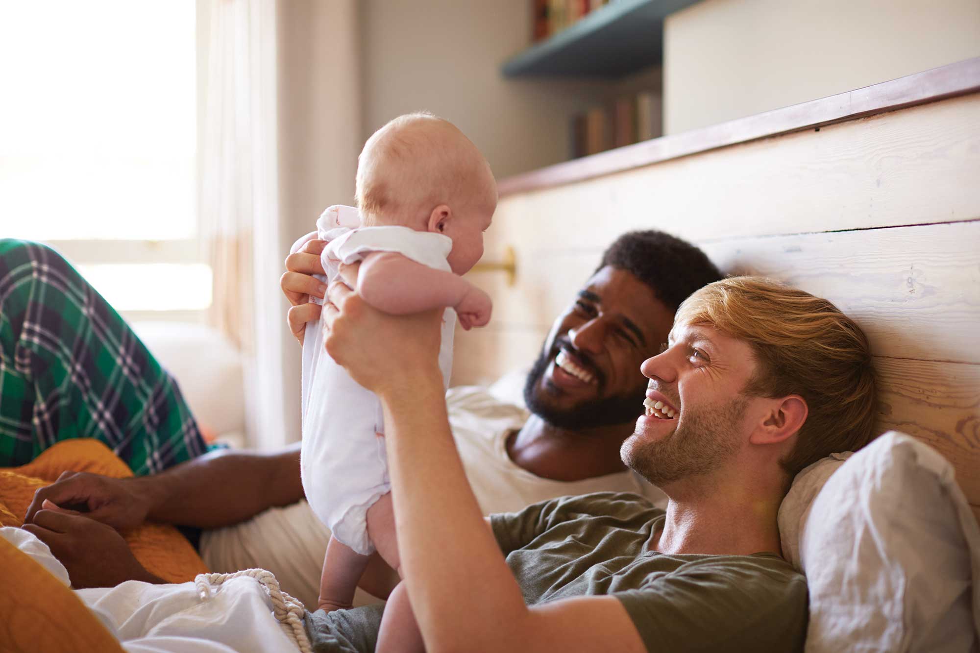 Two joyful gay parents holding their new born baby