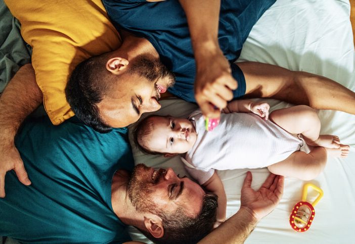 image of men with baby on bed